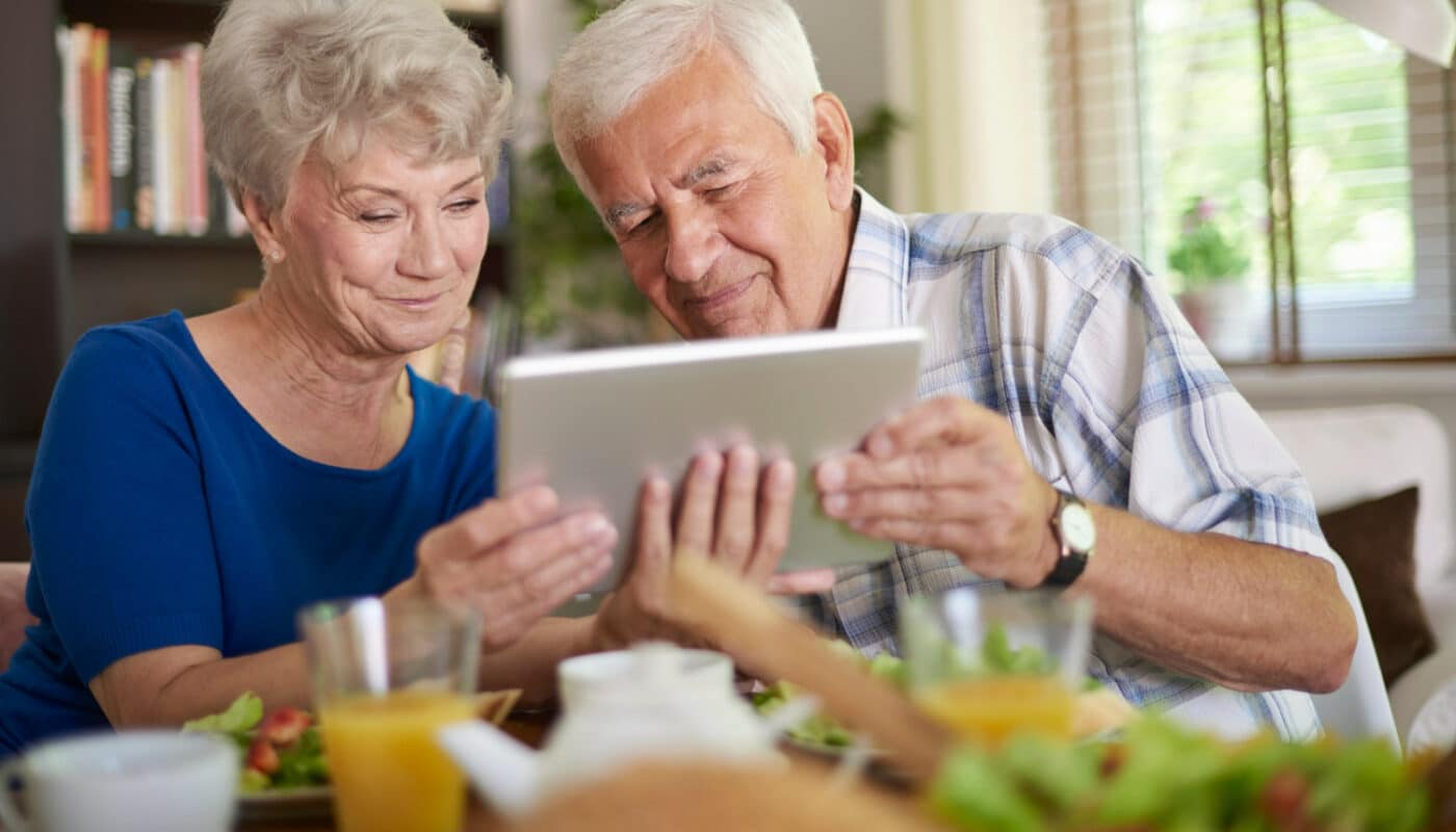 couple de senior qui utilise une tablette lors du petit dejeuner