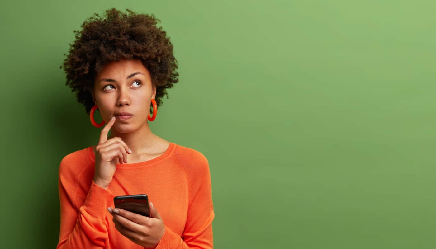 femme qui doute avec son téléphone portable
