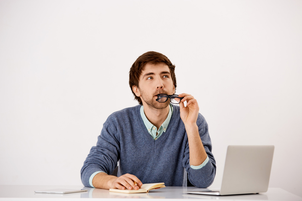 homme qui réfléchit avec ses lunettes dans la bouche