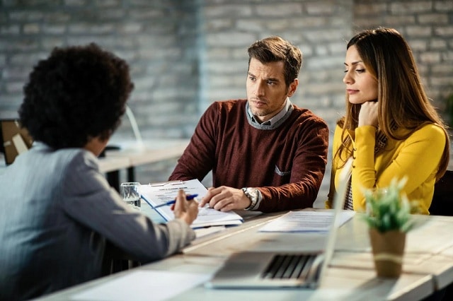 2 jeunes couples avec une agente bancaire faisant l'analyse de la possibilité de faire un crédit