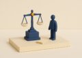 Maquette diorama d'une balance de justice indigo sur un socle avec des dossiers miniatures, illustration d'un avocat specialise en credit a la consommation