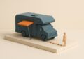 Maquette d un camping-car avec un auvent orange court et une longue file de jetons au sol, illustrant une garantie plus courte que le credit
